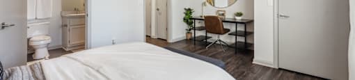 A bedroom with a large bed and a desk with a chair.