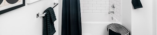 a white bathroom with a black shower curtain and a white tub at OLiVE DTLA in CA 90015