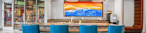 a dining room with blue chairs and a table with a colorful painting at South Side Flats, Dallas, Texas