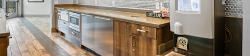 a wet bar with a refrigerator and a painting on the wall at South Side Flats, Dallas, Texas