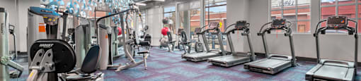 a gym with treadmills and other exercise equipment in a building with windows at South Side Flats, Dallas, 75215