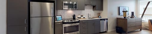 a kitchen with stainless steel appliances and gray cabinets at OLiVE DTLA in Los Angeles, 90015
