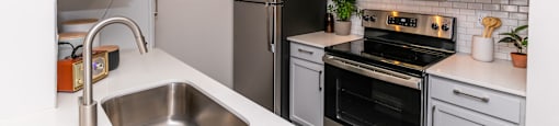a kitchen with stainless steel appliances and white cabinets at Briarcliff Apartments, Georgia