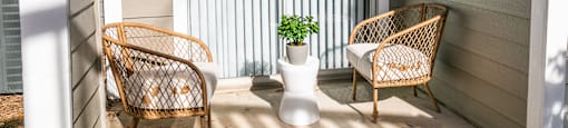 a porch with two rattan chairs and a vase with a plant at Briarcliff Apartments, Atlanta