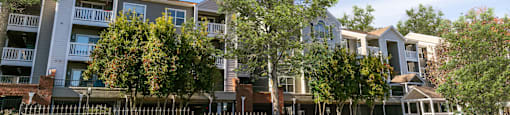 an apartment building with a fence and trees in front of it at Briarcliff Apartments, Atlanta