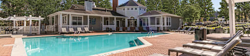 a swimming pool with lounge chairs and a house in the background at Briarcliff Apartments, Georgia