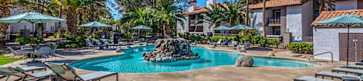 a resort style swimming pool with a rock in the middle of it