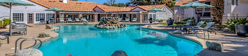 a large swimming pool with chairs and umbrellas at the resort
