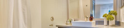 a bathroom with a tub and a sink and a mirror at Mirasol Apartments, Las Vegas
