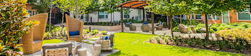 a yard with furniture and trees in front of an apartment building at South Side Flats, Dallas, Texas