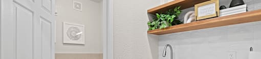 a bathroom with a sink and a toilet and a laundry room with a door open at Switchback on Platte Apartments, Littleton, CO 80120
