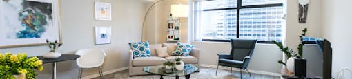 a living room with a couch and a table and a window  at Apartments at Denver Place, Denver, 80202