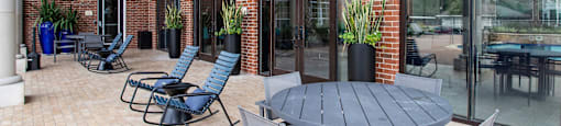a patio with a table and chairs outside of a brick building at Volare at the Woodlands, The Woodlands, Texas