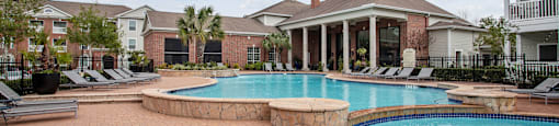 a large swimming pool with a house in the background at Volare at the Woodlands, The Woodlands, TX, 77384