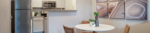 a kitchen with stainless steel appliances and a table with chairs at Volare at the Woodlands, The Woodlands, TX, 77384