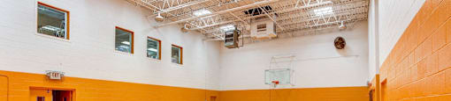 a large gym with a wooden floor and yellow and white walls at Willow Hill Apartments, Justice