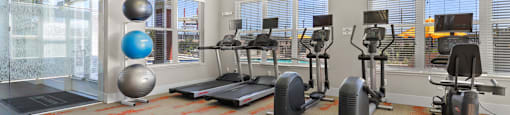 a gym with weights and exercise equipment in a building with large windows at Ridge at Thornton Station Apartments, Thornton, CO