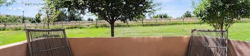a patio with two chairs and a table and a tree at Ridge at Thornton Station Apartments, Thornton