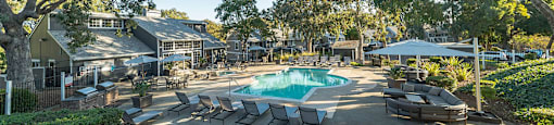 a pool with lounge chairs and trees around it at Bay Village, California, 94590