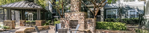 a patio with a stone fireplace and a table and chairs at Deerfield Village, Alpharetta, GA
