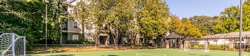 a tennis court with trees and a house in the background at Deerfield Village, Georgia
