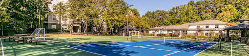 a tennis court with trees and a house in the background at Deerfield Village, Alpharetta, Georgia