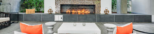 Outdoor dining area with a black chair in front of a fireplace at G12 Apartments in Los Angeles, CA
