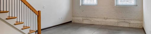 an empty room with two windows and a staircase at Highland Mill Lofts, Charlotte, North Carolina