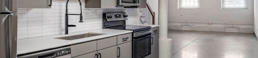 a kitchen with white counter tops and stainless steel appliances at Highland Mill Lofts, Charlotte, 28205