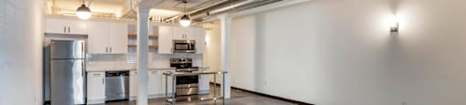 an empty room with a kitchen and a table in the middle at Highland Mill Lofts, Charlotte, North Carolina
