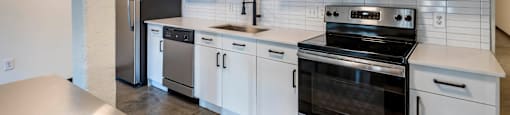 a kitchen with white cabinets and stainless steel appliances at Highland Mill Lofts, Charlotte