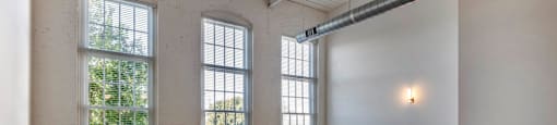 an empty room with three large windows and a table at Highland Mill Lofts, Charlotte, NC