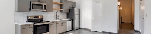 a kitchen with stainless steel appliances and white walls at Highland Mill Lofts, Charlotte
