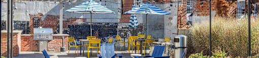a patio with blue and yellow chairs and umbrellas at Highland Mill Lofts, Charlotte, North Carolina