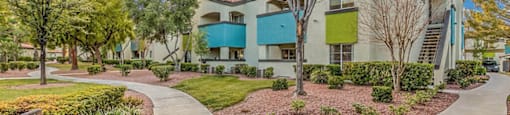 an exterior view of a building with a sidewalk and benches at Mirasol Apartments, Las Vegas, Nevada