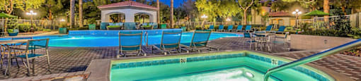 a pool with chairs and a hot tub at night at Mirasol Apartments, Las Vegas, NV 89119