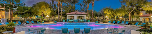 a large swimming pool with chairs and a jacuzzi at night at Mirasol Apartments, Las Vegas, NV