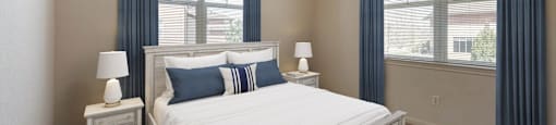 a bedroom with a bed and two windows at Switchback on Platte Apartments, Littleton, 80120