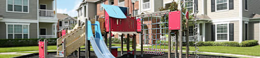 an outdoor playground in front of an apartment building at Volare at the Woodlands, The Woodlands, TX, 77384