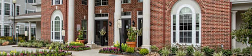 a parking lot in front of a brick building with white columns at Volare at the Woodlands, The Woodlands, 77384