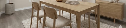 A dining room with a table, chairs, and a plant.