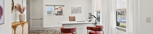 a living area with a desk and chairs and a window
