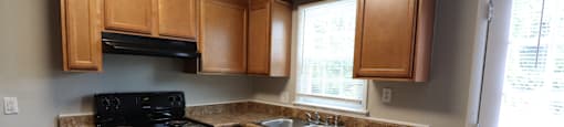 A kitchen with wooden cabinets and a black stove top oven.