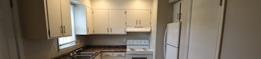 A kitchen with white cabinets and a white refrigerator.