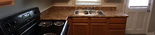 A kitchen with wooden cabinets and a black stove top oven.