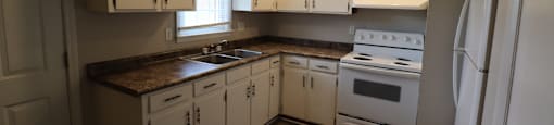 A kitchen with white cabinets and a brown countertop.