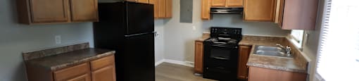 A kitchen with wooden cabinets and a black refrigerator.