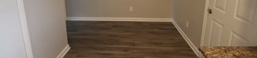 A room with wooden flooring and a door on the right.