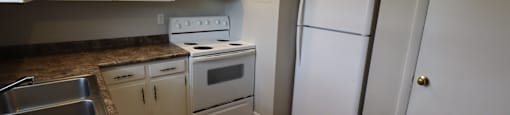 A kitchen with a white fridge and white cabinets.