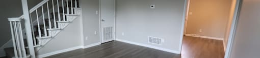 A room with a staircase and wooden flooring.